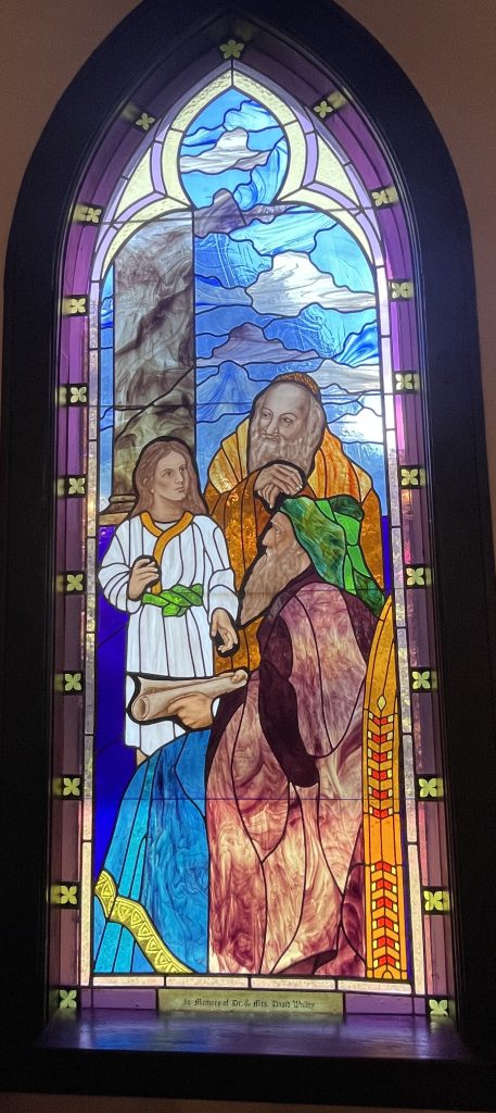 Stained glass window depicting young Jesus with scholars