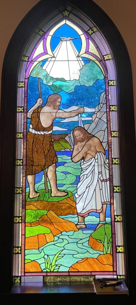 Stained glass window depicting Jesus being baptized